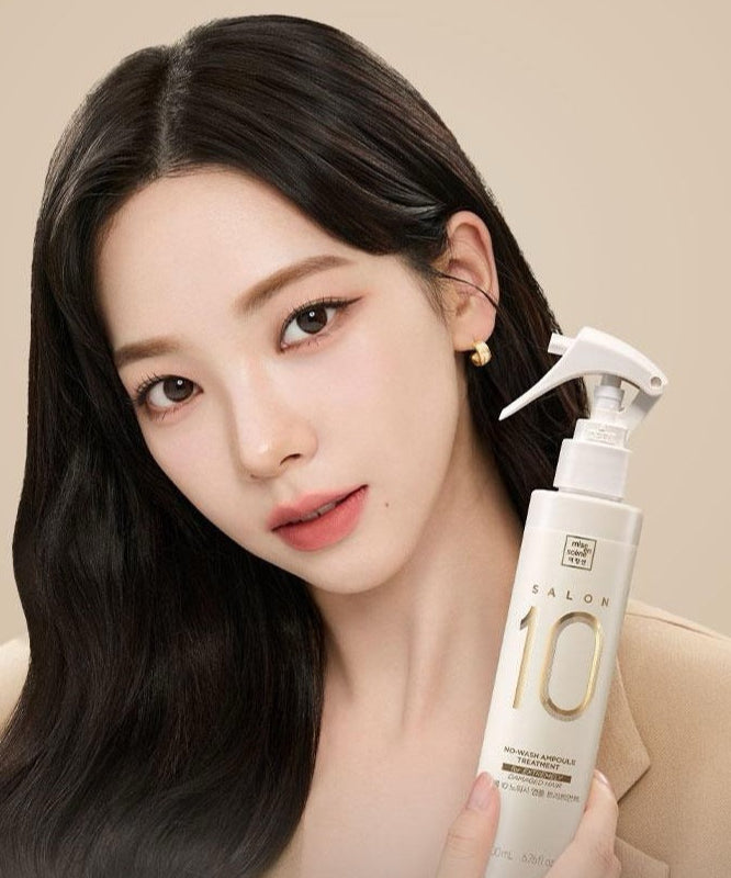 Décris l'image en français : MISE EN SCENE Salon 10 No-Wash Extreme Damage Ampoule Treatment 200ml, flacon tenu par une femme, fond beige.
