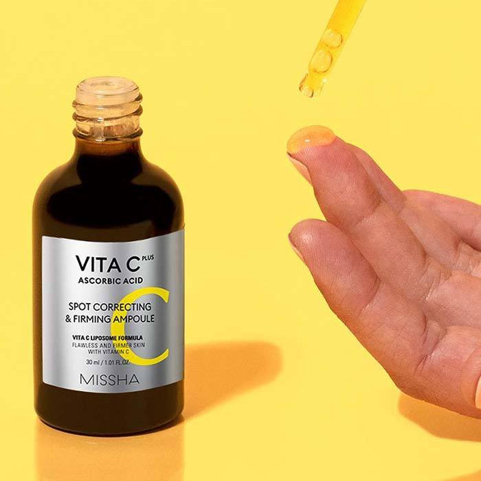 MISSHA  Vita C Plus Blemish C Elasticity Ampoule 40ml, flacon sur fond jaune, goutte et main tenant le sérum