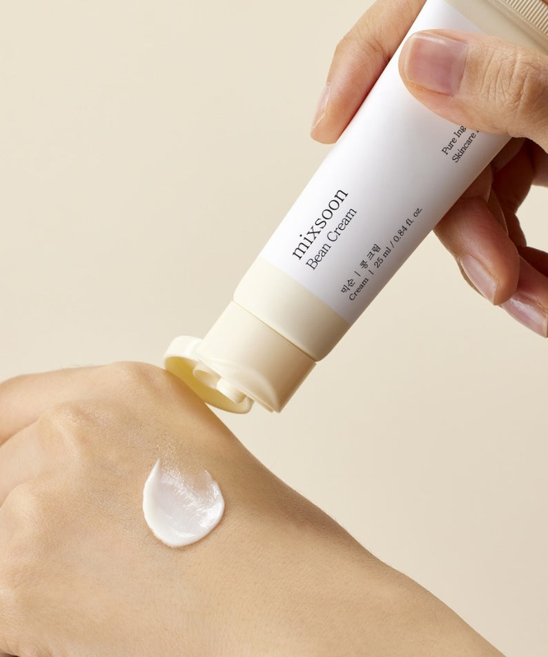 Main appliquant MIXSOON Bean Cream 25ml de la marque MIXSOON sur la peau, crème blanche sur fond clair.