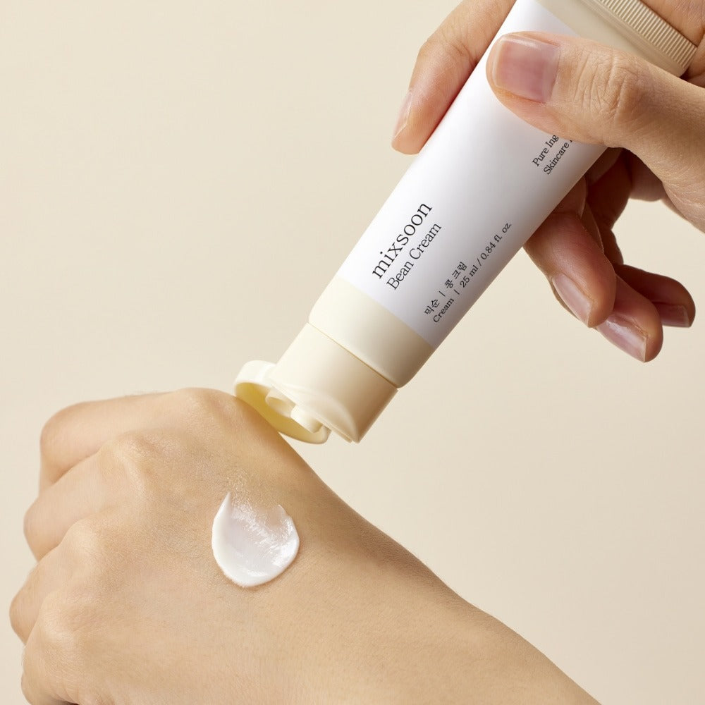 Main appliquant MIXSOON Bean Cream 25ml de la marque MIXSOON sur la peau, crème blanche sur fond clair.