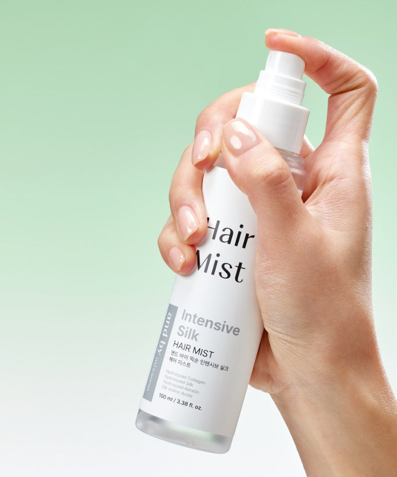 Main tenant MIXSOON Intensive Silk Hair Mist 100ml, flacon blanc sur fond vert, produit capillaire de la marque MIXSOON