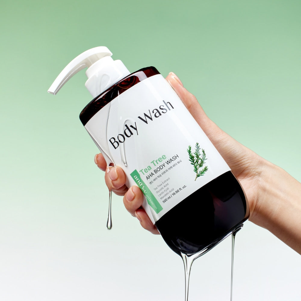 MIXSOON Tea Tree AHA Body Wash 500ml, main tenant le flacon sur fond vert, produit douche illustré.