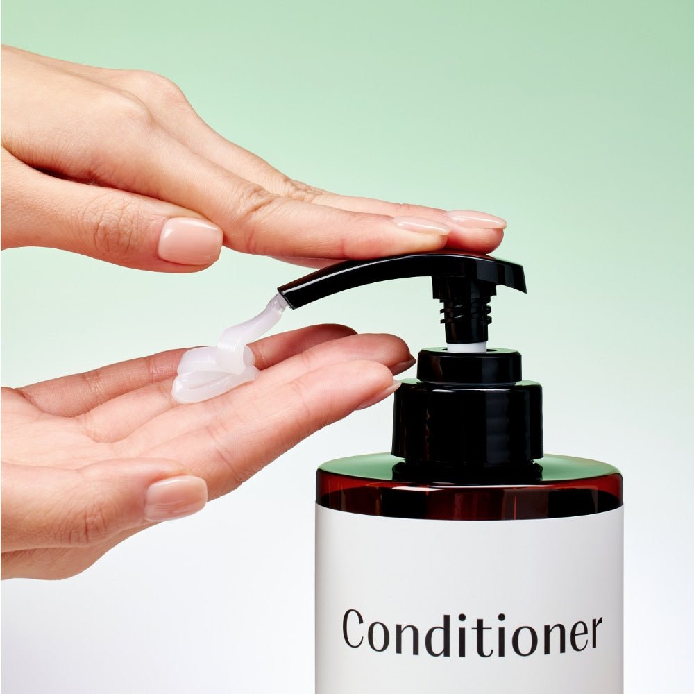 Main appliquant le produit MIXSOON Tea Tree Moisture Conditioner 500ml, marque MIXSOON sur flacon pompe, fond vert pastel.