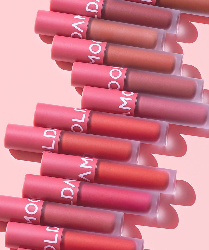 Collection de MOOLDA Tattoo Fixing Lip Tint en différentes nuances sur fond rose.