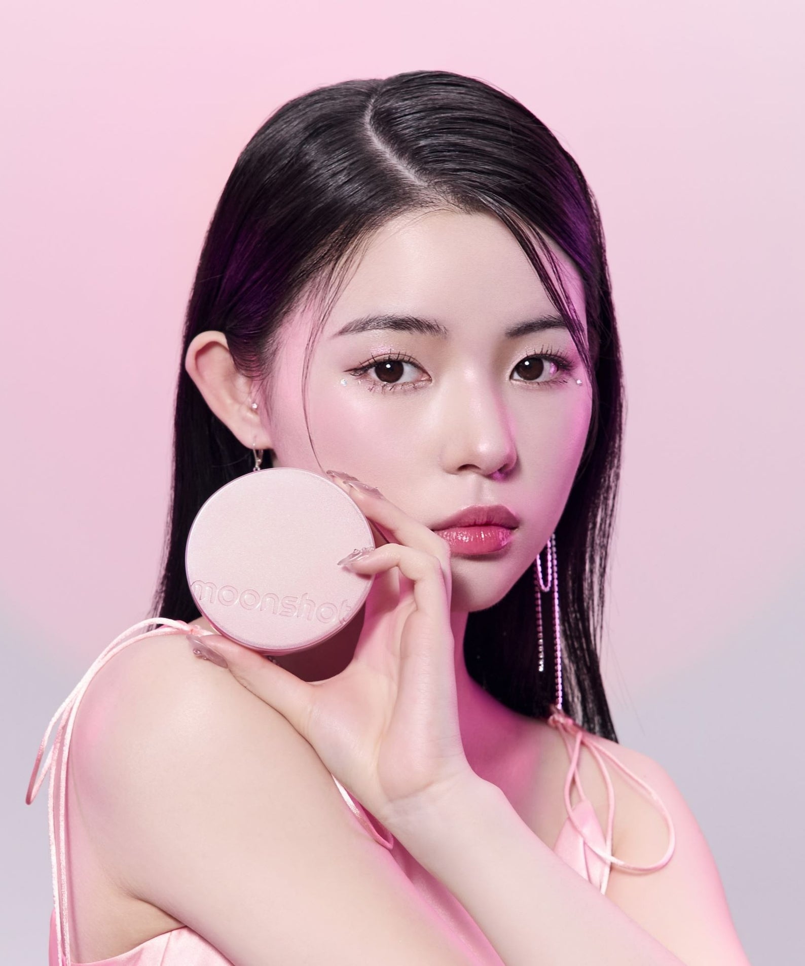 MOONSHOT Conscious Fit Cushion Foundation Pink Moon Edition, marque MOONSHOT, femme tenant la poudre sur fond rose