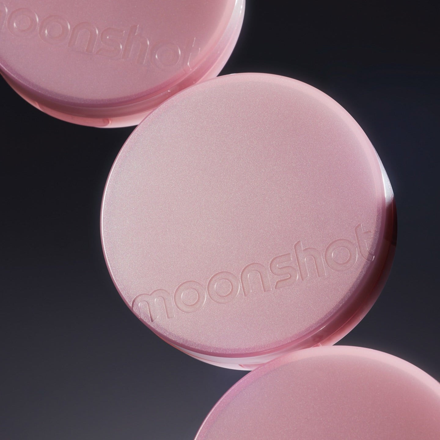 Décris l'image en français : MOONSHOT Conscious Fit Cushion Foundation Pink Moon Edition, boîtiers roses sur fond noir.