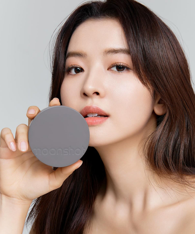 Modèle tenant le MOONSHOT Conscious Fit Matte Cushion Foundation, produit maquillage mat nacré.