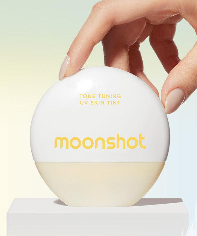 Produit MOONSHOT Tone Tuning UV Skin Tint SPF50+ PA++++ présenté avec une main délicate sur un fond pastel élégant.