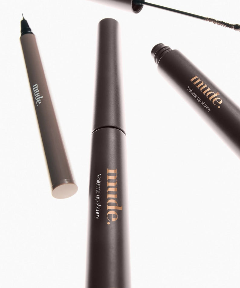 MUDE Mood Volume Up Skinny Mascara de MUDE, gros plan sur le tube noir et l’applicateur sur fond clair.