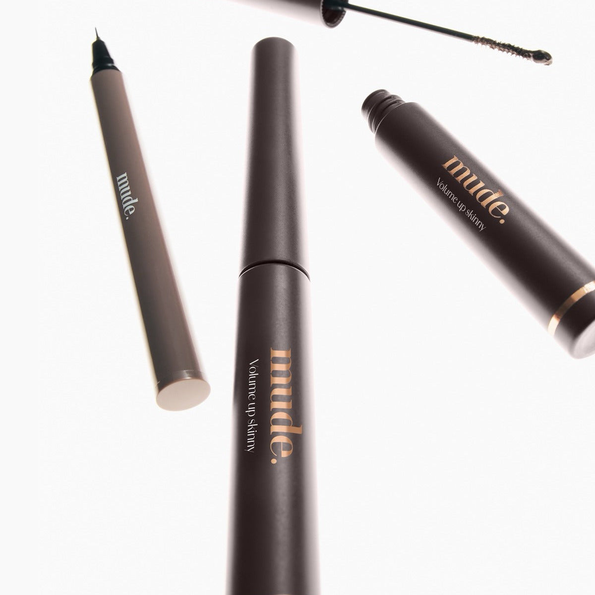 MUDE Mood Volume Up Skinny Mascara de MUDE, gros plan sur le tube noir et l’applicateur sur fond clair.