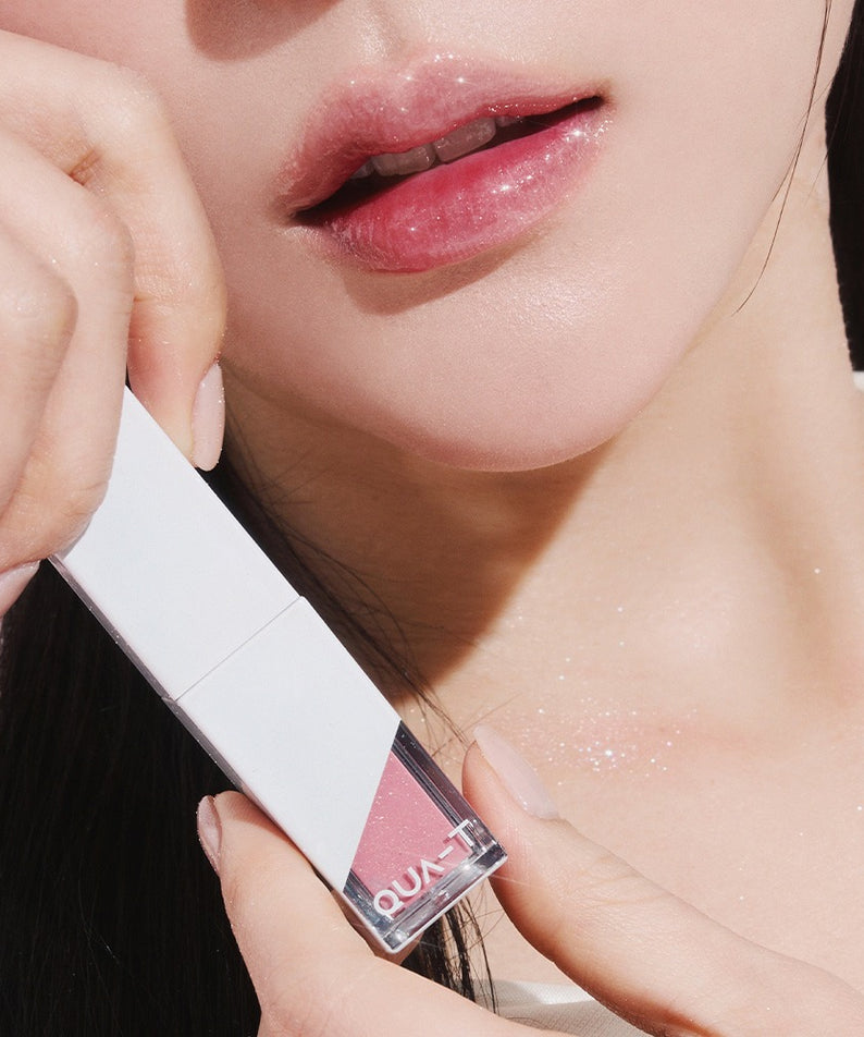 Femme appliquant QUA-T The Glass Tattoo Tint Pearl Edition, offrant une finition brillante et élégante sur ses lèvres.