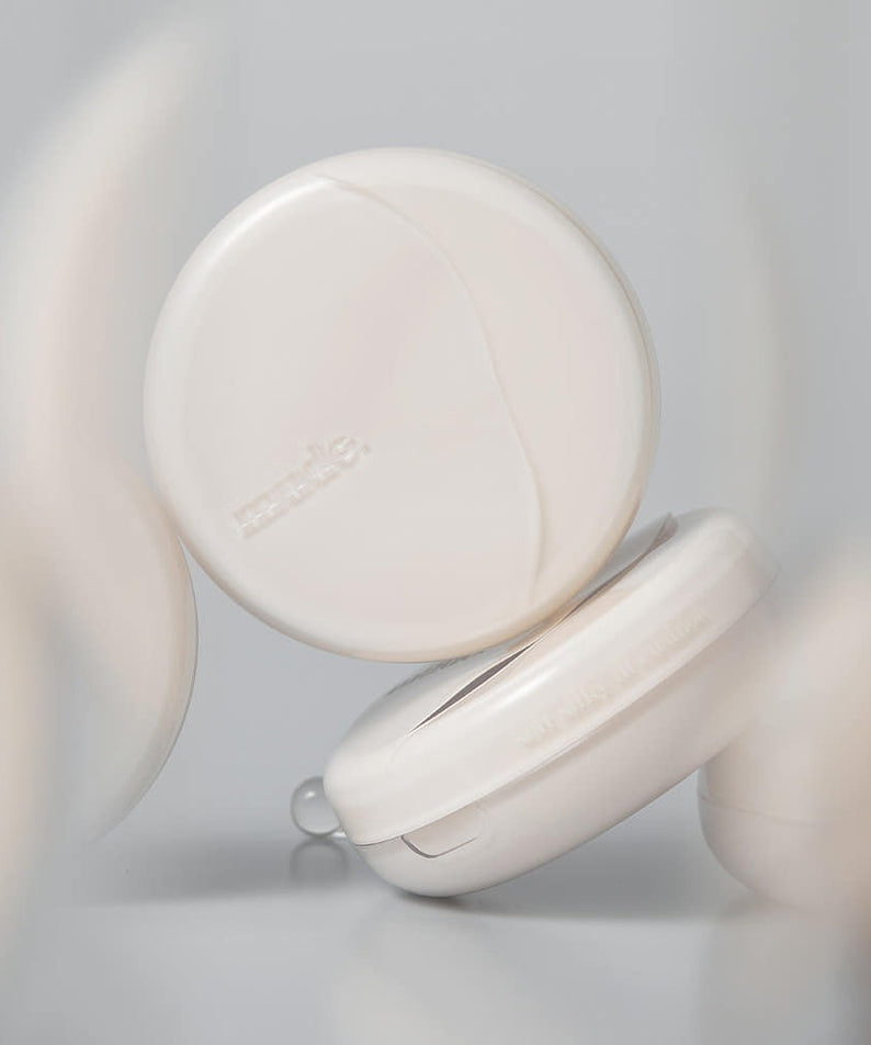 Décris l'image en français en montrant Mude Soft Silky Fit Cushion SPF50+ PA+++ Product + Refill, poudre compacte blanche.