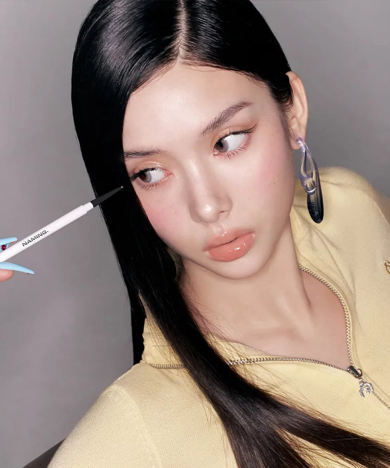 NAMING Pencil Slim Liner de la marque NAMING, maquillage des yeux: la femme trace une ligne au stylo eyeliner.