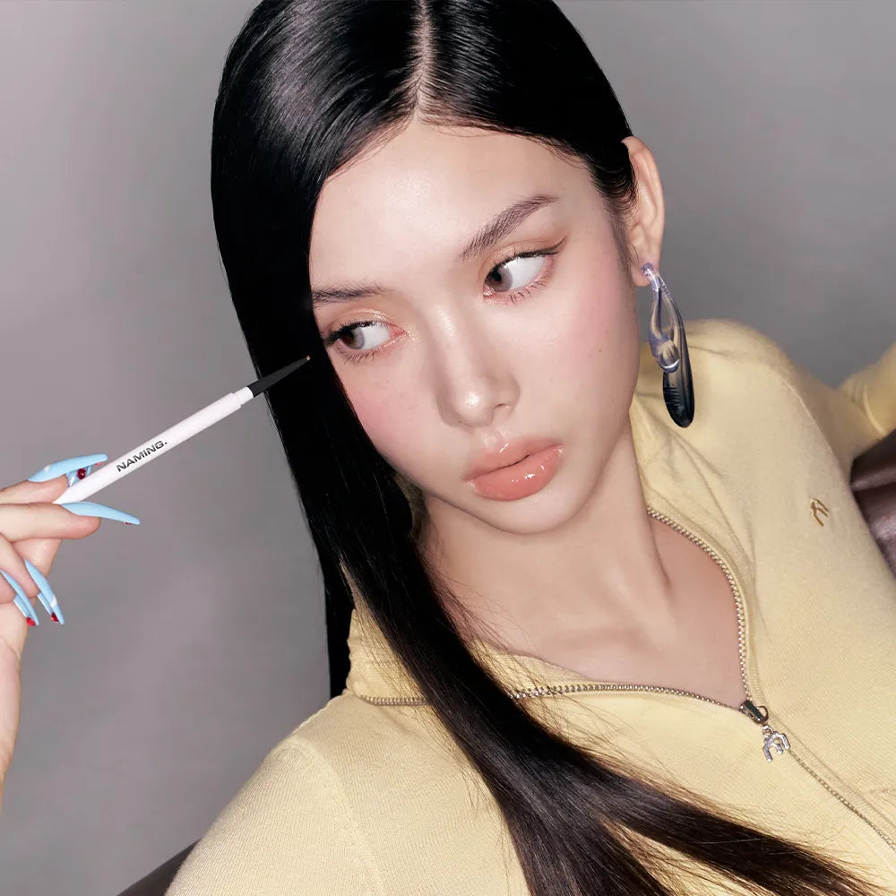 NAMING Pencil Slim Liner de la marque NAMING, maquillage des yeux: la femme trace une ligne au stylo eyeliner.