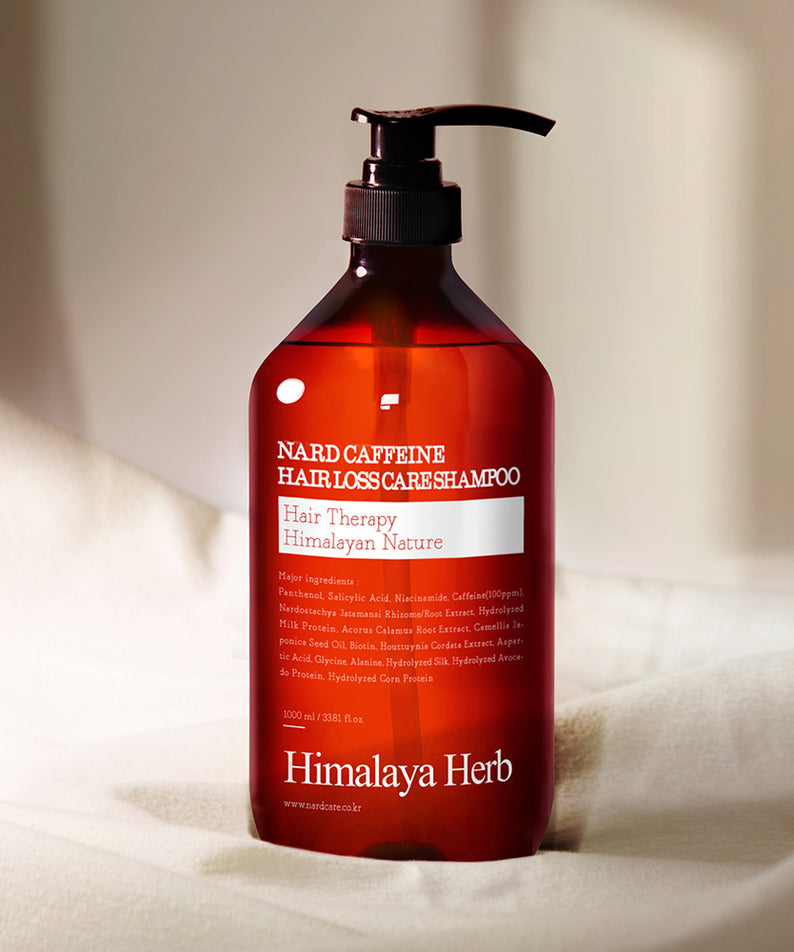 NARD Caffeine Anti-Hair Loss Shampoo 1000ml de NARD, flacon rouge avec pompe, sur linge blanc, ambiance salle de bain.