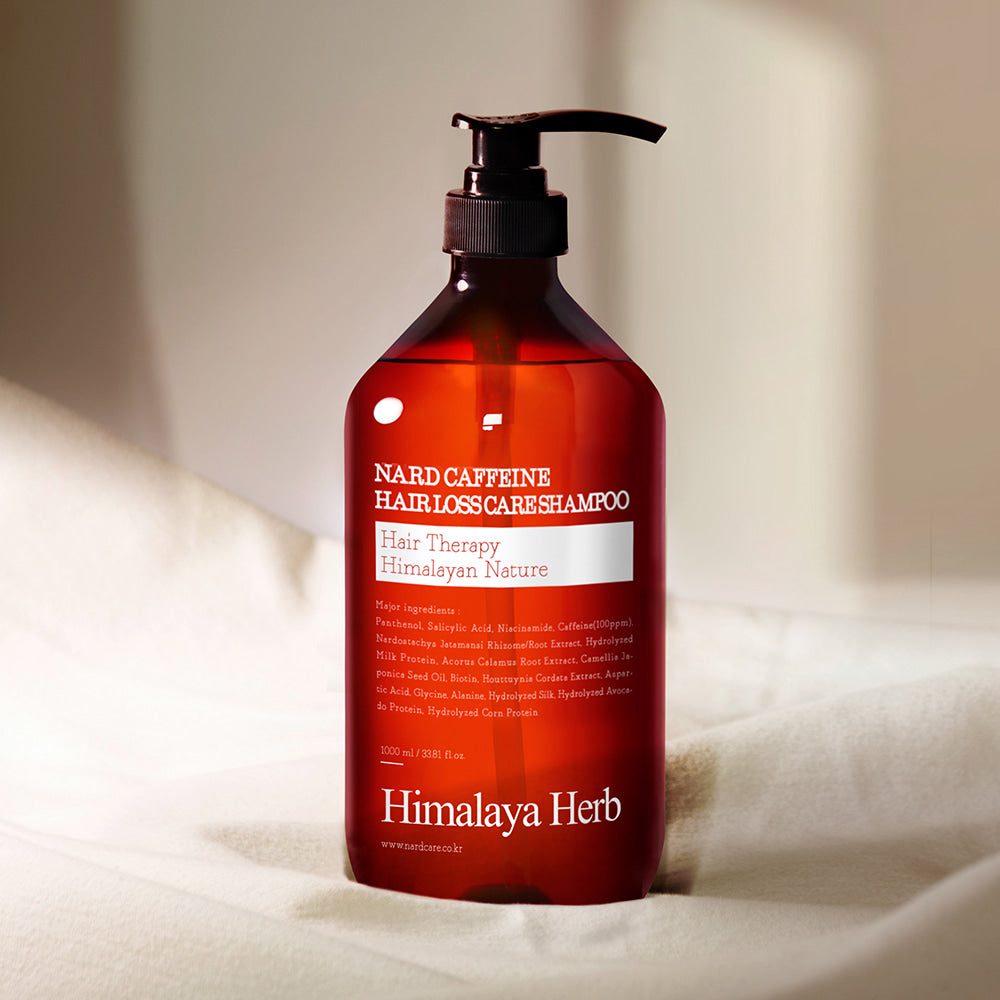 NARD Caffeine Anti-Hair Loss Shampoo 1000ml de NARD, flacon rouge avec pompe, sur linge blanc, ambiance salle de bain.