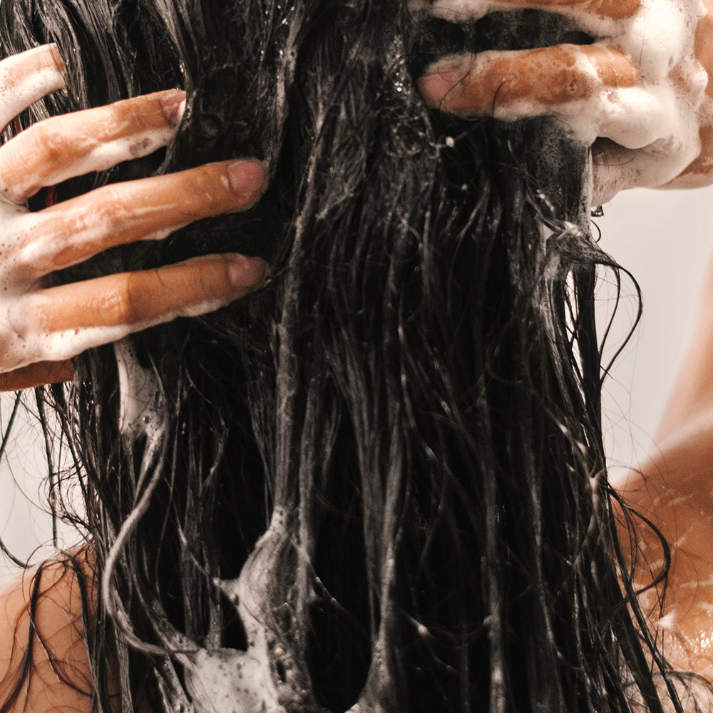 NARD Damage RX Shampoo 500ml, marque NARD : cheveux avec mousse sous douche, mains savonneuses en gros plan