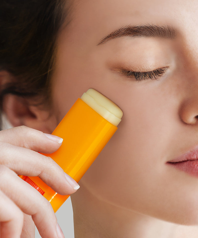 NARD Perfect Shield Sun Stick 22g, femme applique un stick solaire NARD en gros plan sur la peau, fond clair.