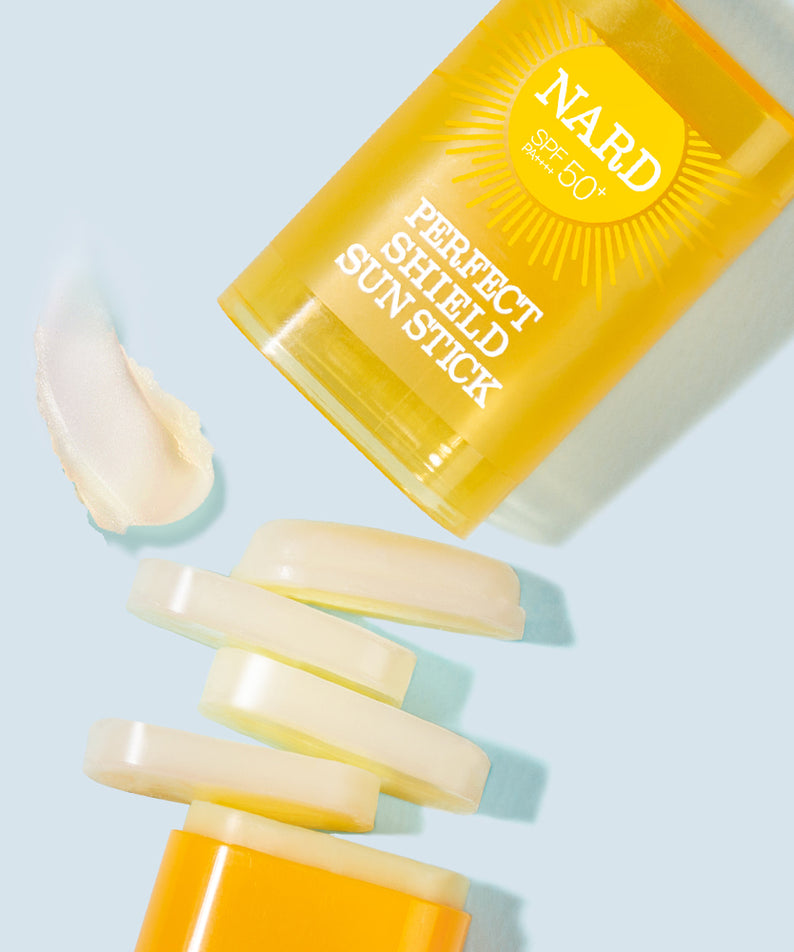 NARD Perfect Shield Sun Stick 22g de NARD, stick solaire jaune sur fond bleu clair, texture crème visible.
