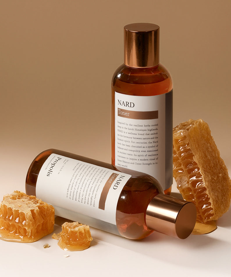 NARD Propolis Infusing Toner 200ml de NARD, bouteille brune sur fond beige avec morceaux de propolis à côté.