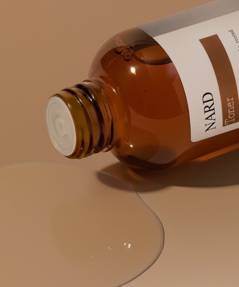NARD Propolis Infusing Toner 200ml de NARD, flacon ambre verse sur fond beige, ambiance beauté spa.
