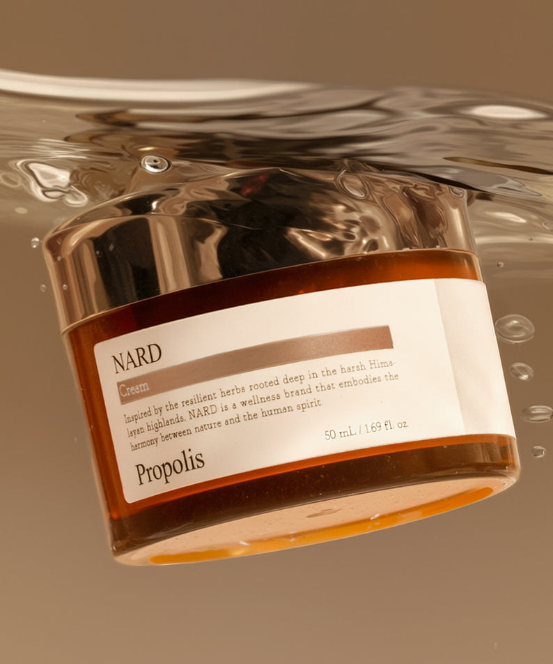 NARD Propolis Nourishing Cream 50ml, pot crème doré NARD sur fond beige, gouttes et reflets, contexte soins visage.