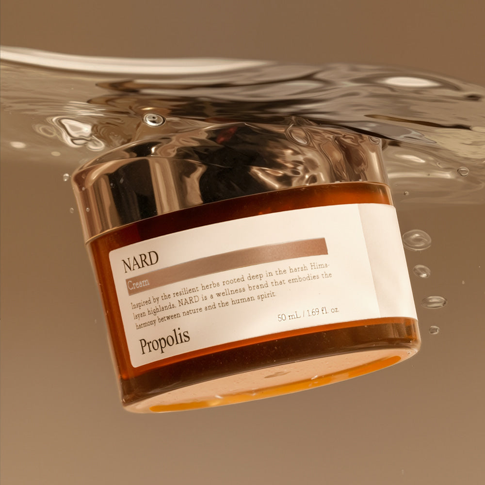 NARD Propolis Nourishing Cream 50ml, pot crème doré NARD sur fond beige, gouttes et reflets, contexte soins visage.
