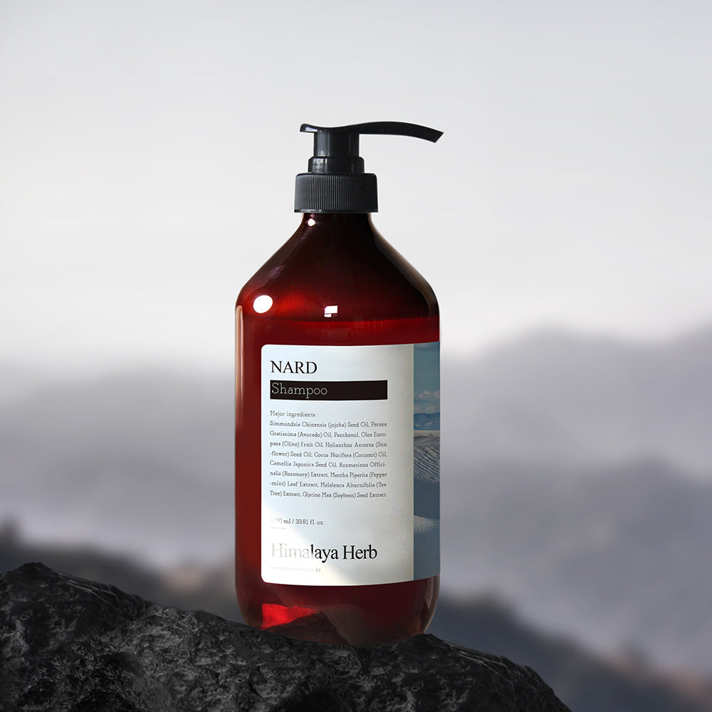 NARD Refresh Perfumed Shampoo 1000ml : flacon NARD sur rocher, ambiance montagne, style photo produit en extérieur.