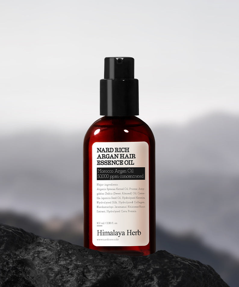 NARD Rich Argan Hair Essence Oil 100ml NARD sur pierre sombre, flacon noir et rouge, décor montagne, photo produit