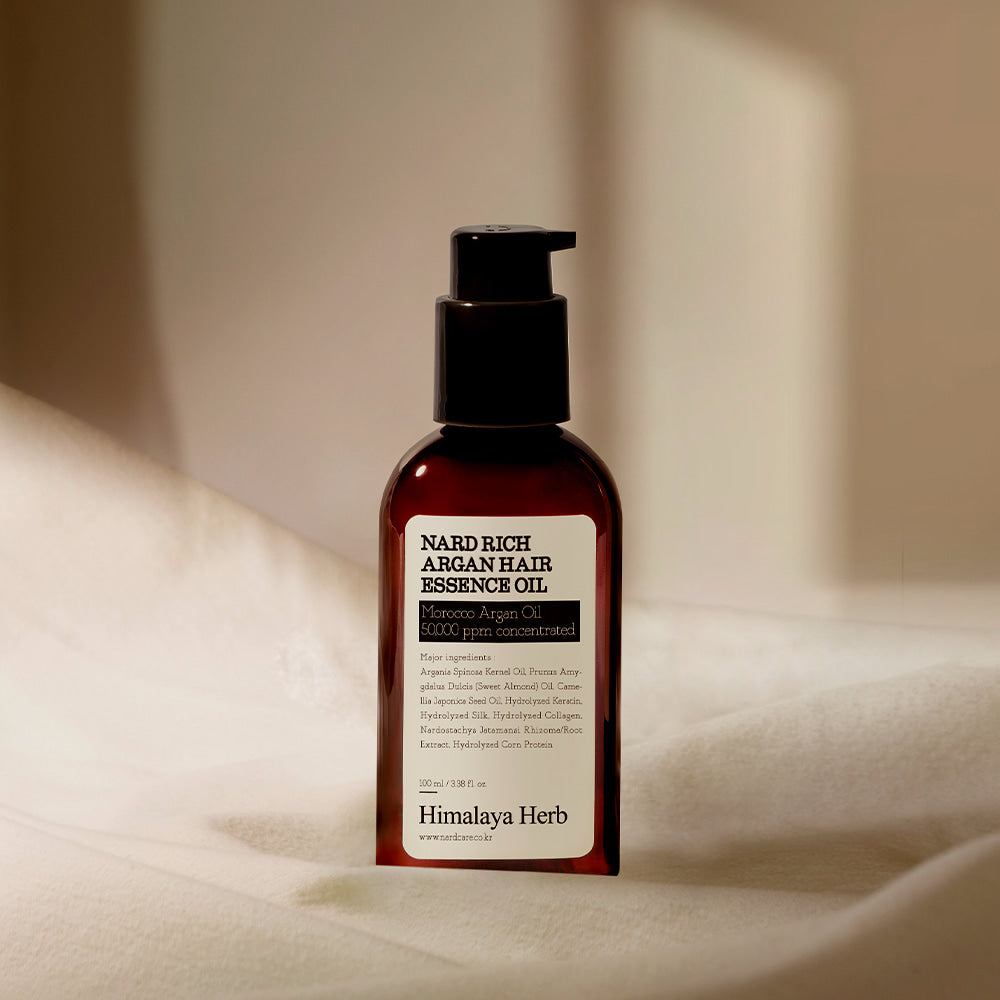 NARD Rich Argan Hair Essence Oil 100ml NARD, flacon brun sur tissu beige, contexte soin capillaire.