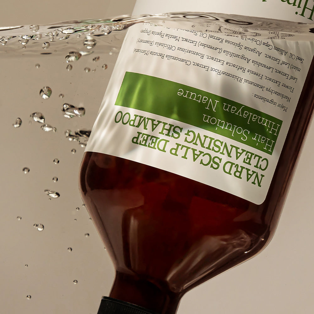 NARD Scalp Dandruff Deep Cleansing Shampoo 1000ml, bouteille brune NARD sur fond eau et gouttes, contexte douche salle de bain.