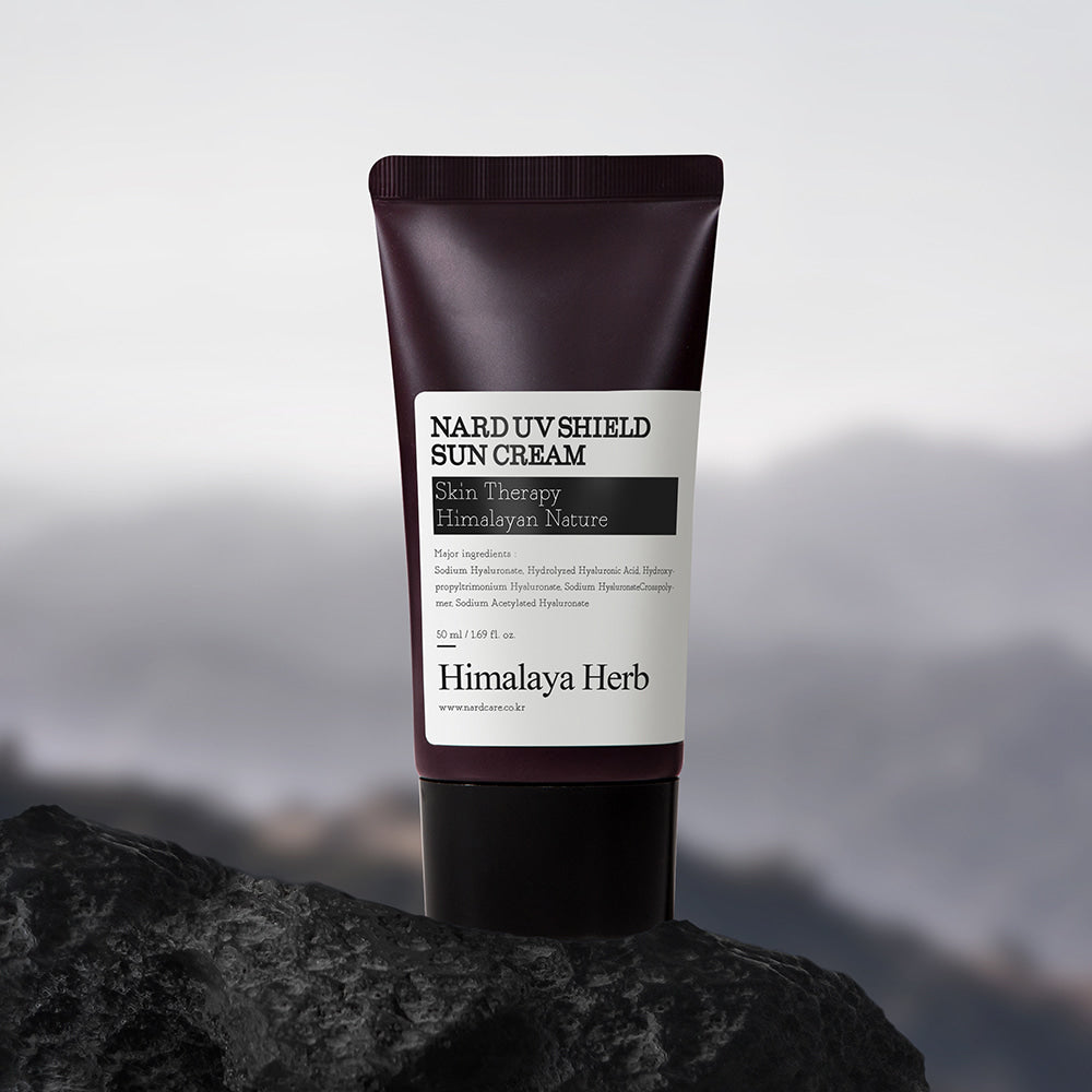NARD UV Shield Sunscreen 50ml de NARD, tube de crème solaire sur rocher devant un paysage montagneux, lumière naturelle.