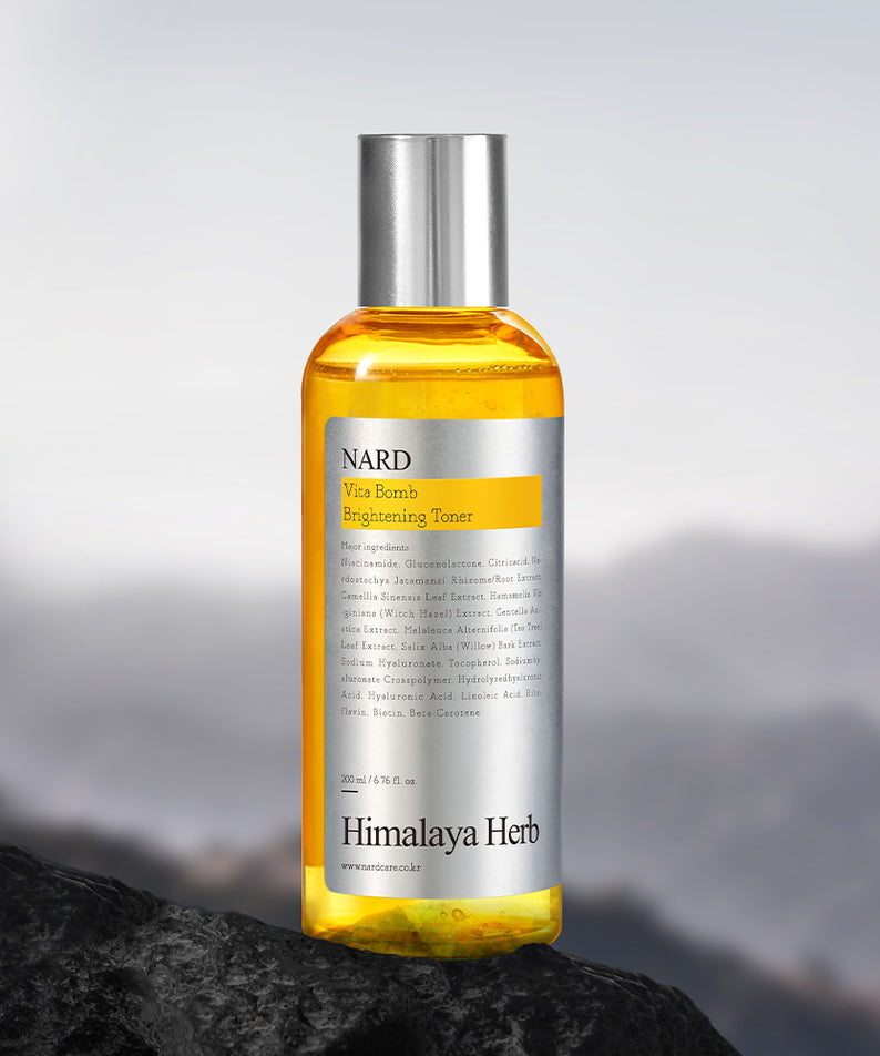 NARD Vita Balm Brightening Toner 200ml de NARD, flacon orange sur rocher avec fond montagne flou