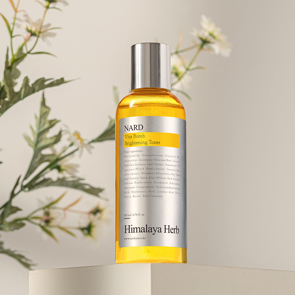 NARD Vita Balm Brightening Toner 200ml NARD, flacon doré sur fond crème avec plantes en contexte beauté naturel