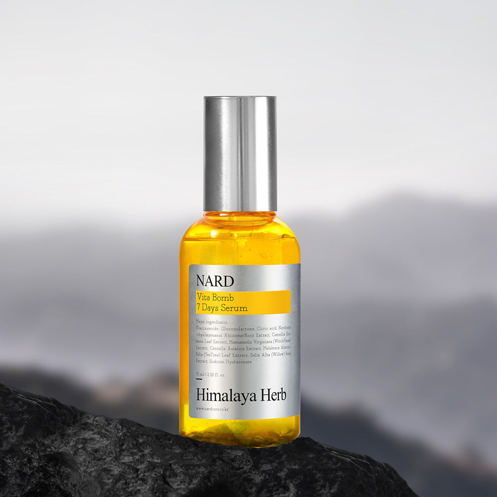 NARD Vita Balm Seven Days Serum 75ml de NARD sur une pierre, flacon jaune au décor montagne, lumière naturelle