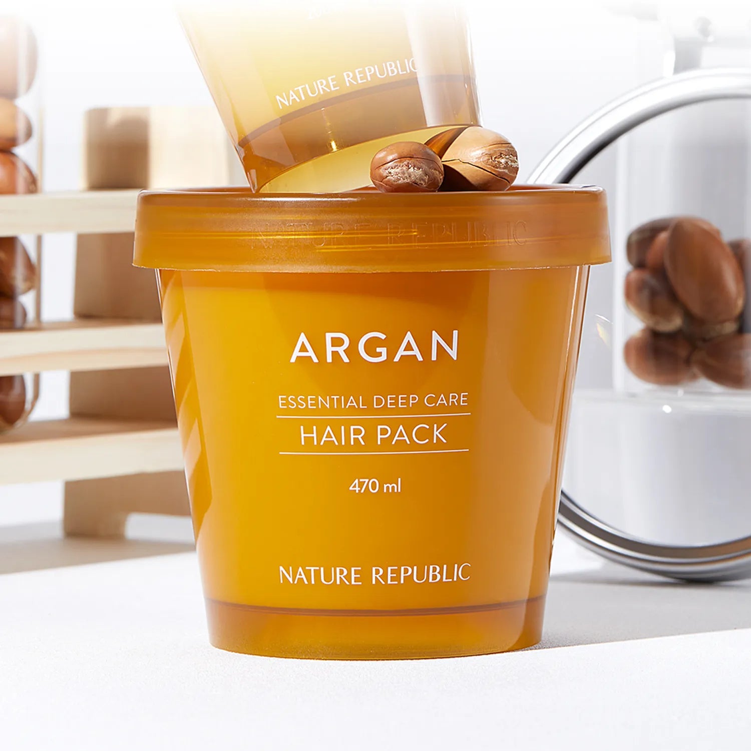 NATURE REPUBLIC Essential Deep Care Hair Pack 470ml, pot argan sur étagère, marque visible, salle de bain moderne, lumière douce.