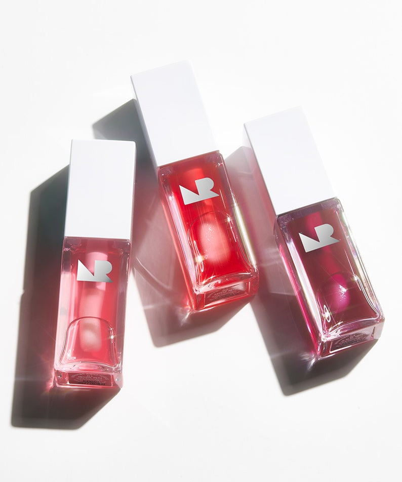Trois flacons de NATURE REPUBLIC Glaze Shine Lip Oil sur fond blanc, ajoutant une touche de brillance et d'hydratation aux lèvres.
