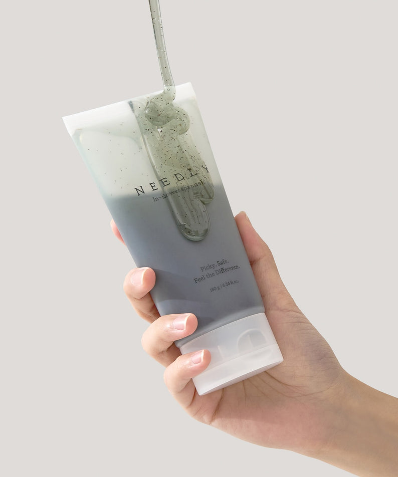 Main tenant NEEDLY Ishower Spa Mask 180g, tube crème en douche, marque NEEDLY, visuel blanc/vert.