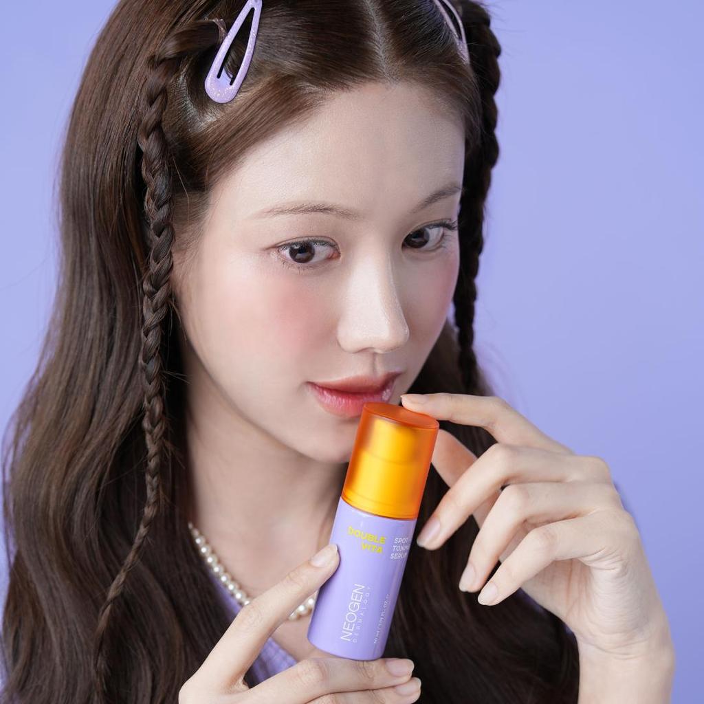 Décris l'image en français : NEOGEN Double Vita Spot Toning Serum 30ml de NEOGEN, femme l’applique sur le visage.