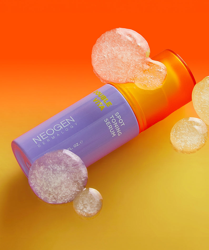 NEOGEN Double Vita Spot Toning Serum 30ml, flacon sur fond orange, pastilles vitaminées, visuel produit NEOGEN.