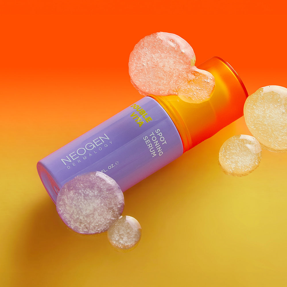 NEOGEN Double Vita Spot Toning Serum 30ml, flacon sur fond orange, pastilles vitaminées, visuel produit NEOGEN.