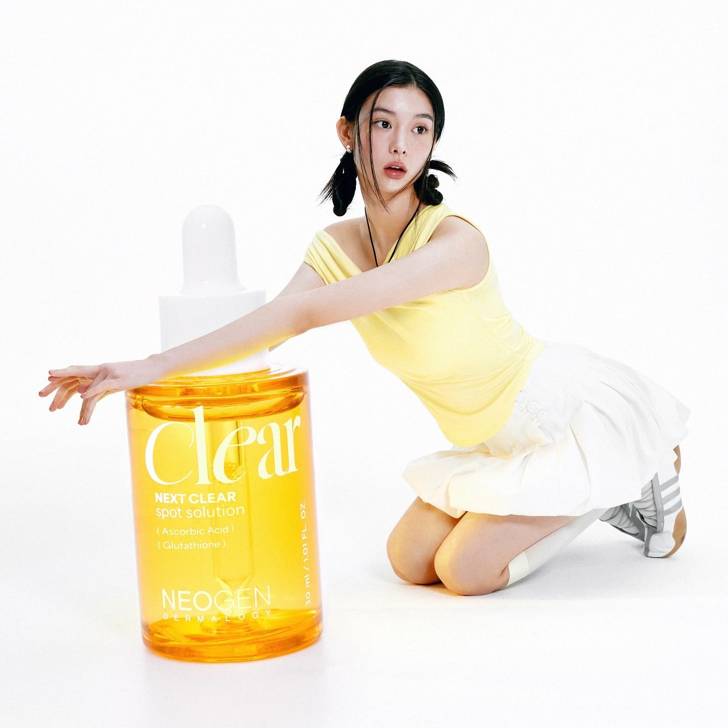 NEOGEN  Next Clear Spot Solution 32ml de Neogen, flacon jaune sur fond blanc avec une femme en séance soin visage.