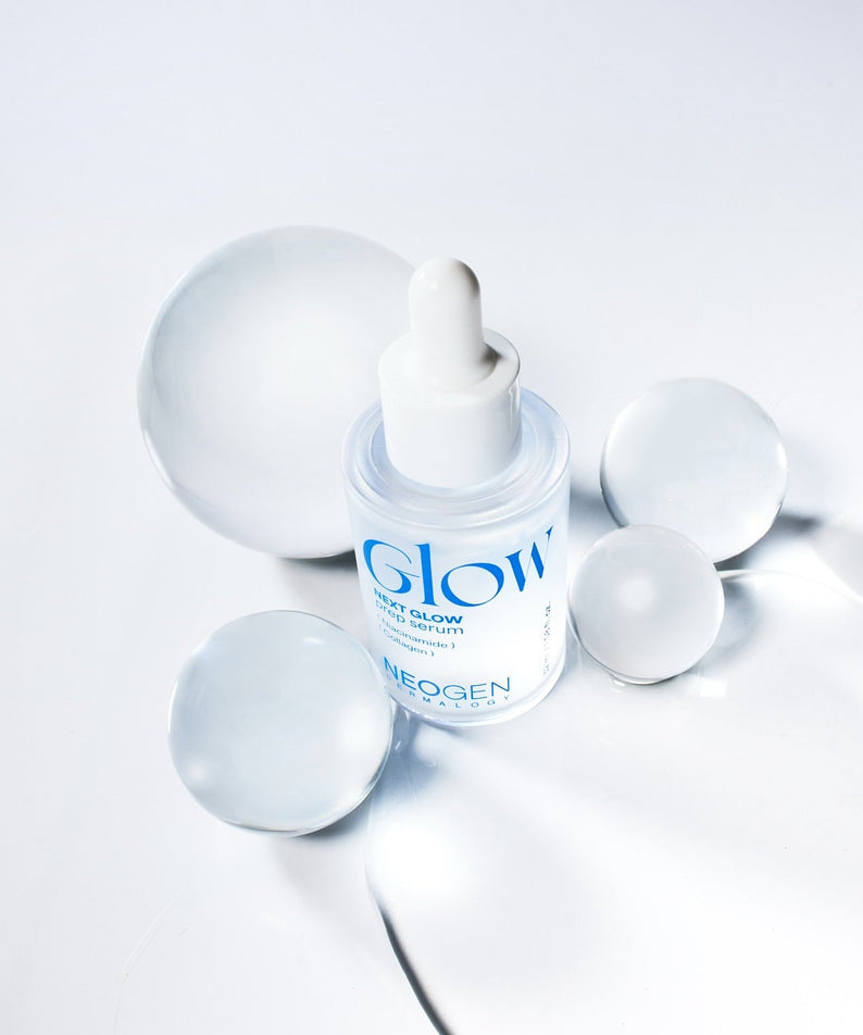 NEOGEN Next Glow Prep Serum 32ml, flacon lumineux sur fond clair avec accessoires cosmétiques, marque NEOGEN en contexte skincare