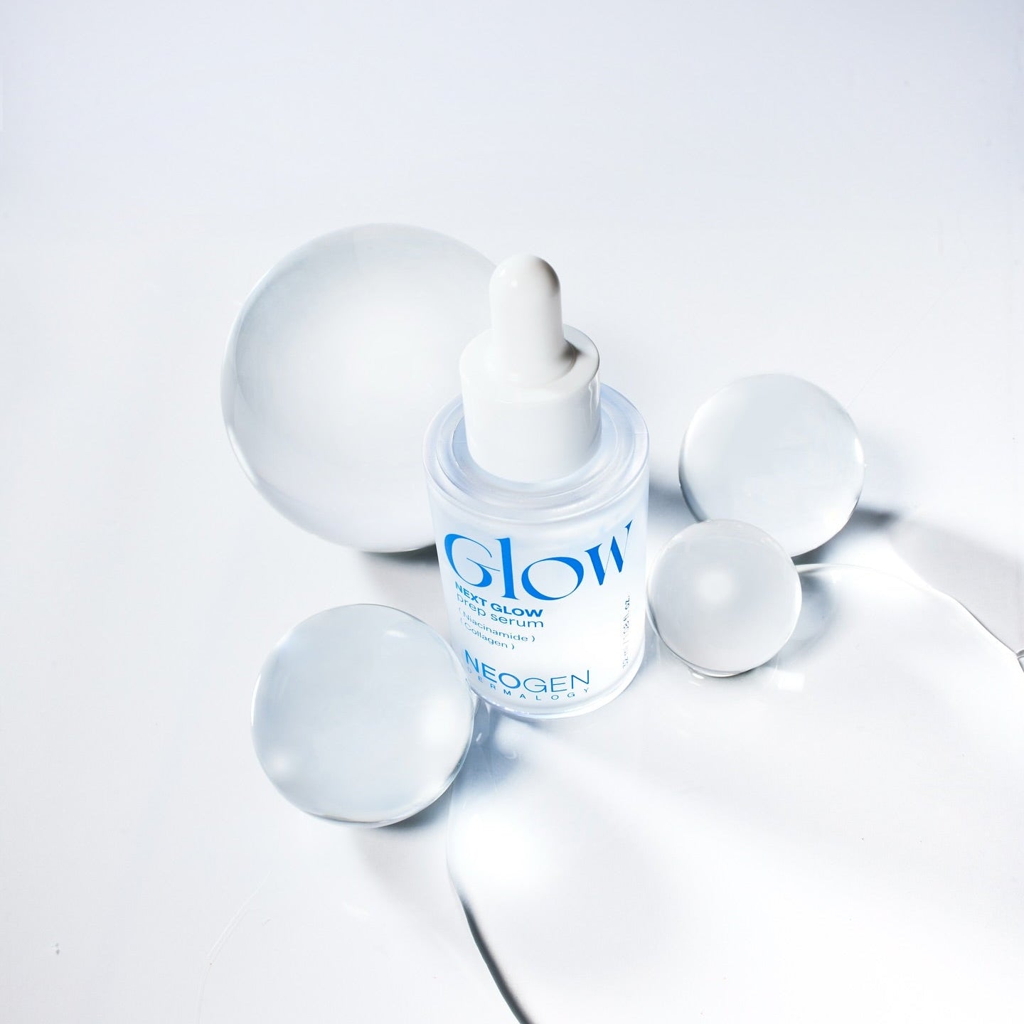 NEOGEN Next Glow Prep Serum 32ml, flacon lumineux sur fond clair avec accessoires cosmétiques, marque NEOGEN en contexte skincare