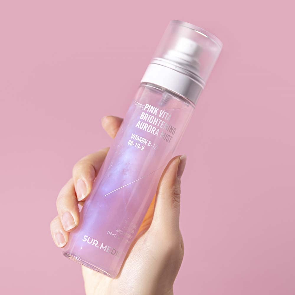Main tenant NEOGEN Pink Vita Aurora Mist 115ml de NEOGEN, flacon rose sur fond rose pastel, contexte beauté/soin.