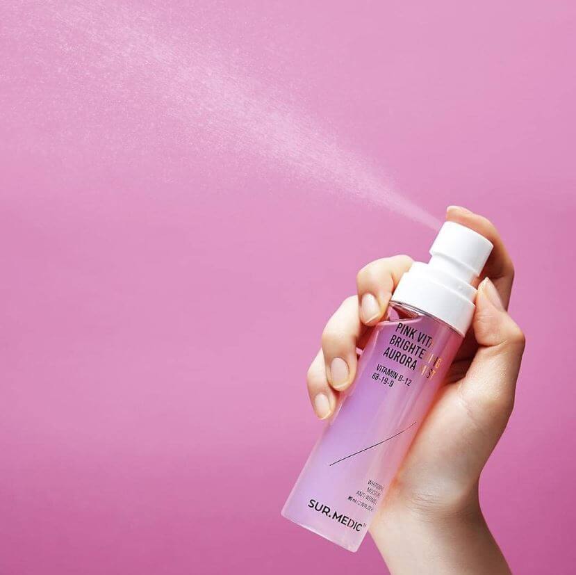 Main tenant NEOGEN Pink Vita Aurora Mist 115ml de la marque NEOGEN, sur fond rose pastel, spray/brume visage