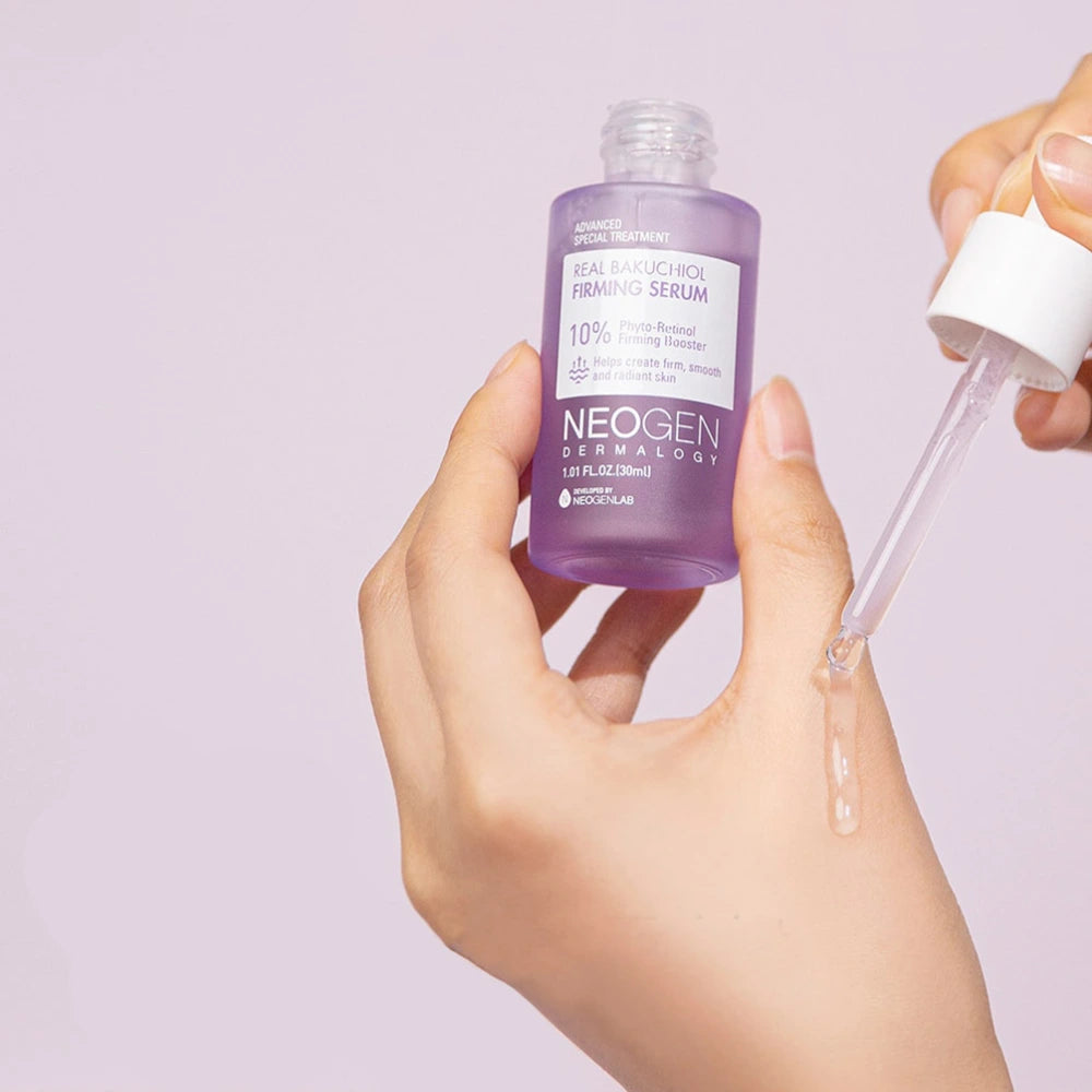 NEOGEN Real Bakuchiol Firming Serum 30ml de la marque NEOGEN, mains appliquant le sérum sur fond violet clair.