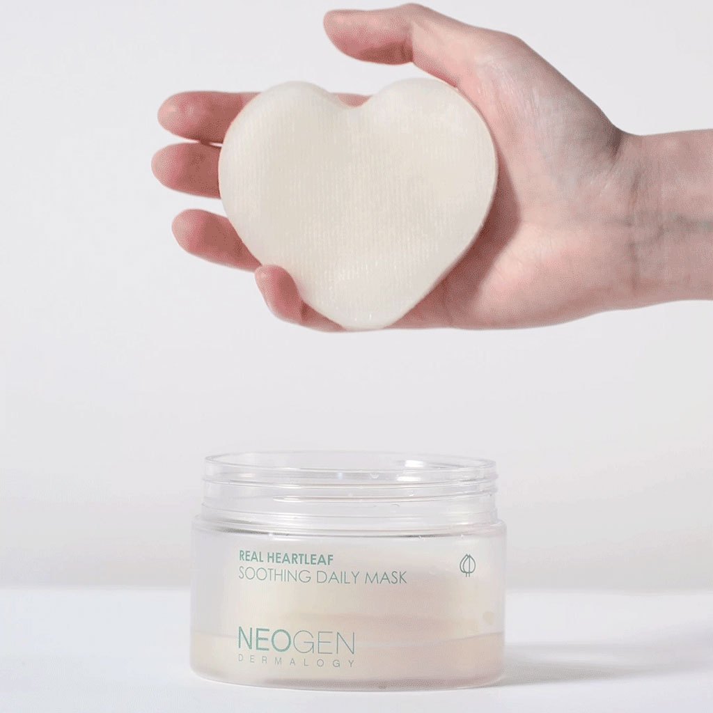 NEOGEN Real Heartleaf Soothing Daily Mask 40 Sheets, masque en tissu cœur tenu en main et pot sur fond clair