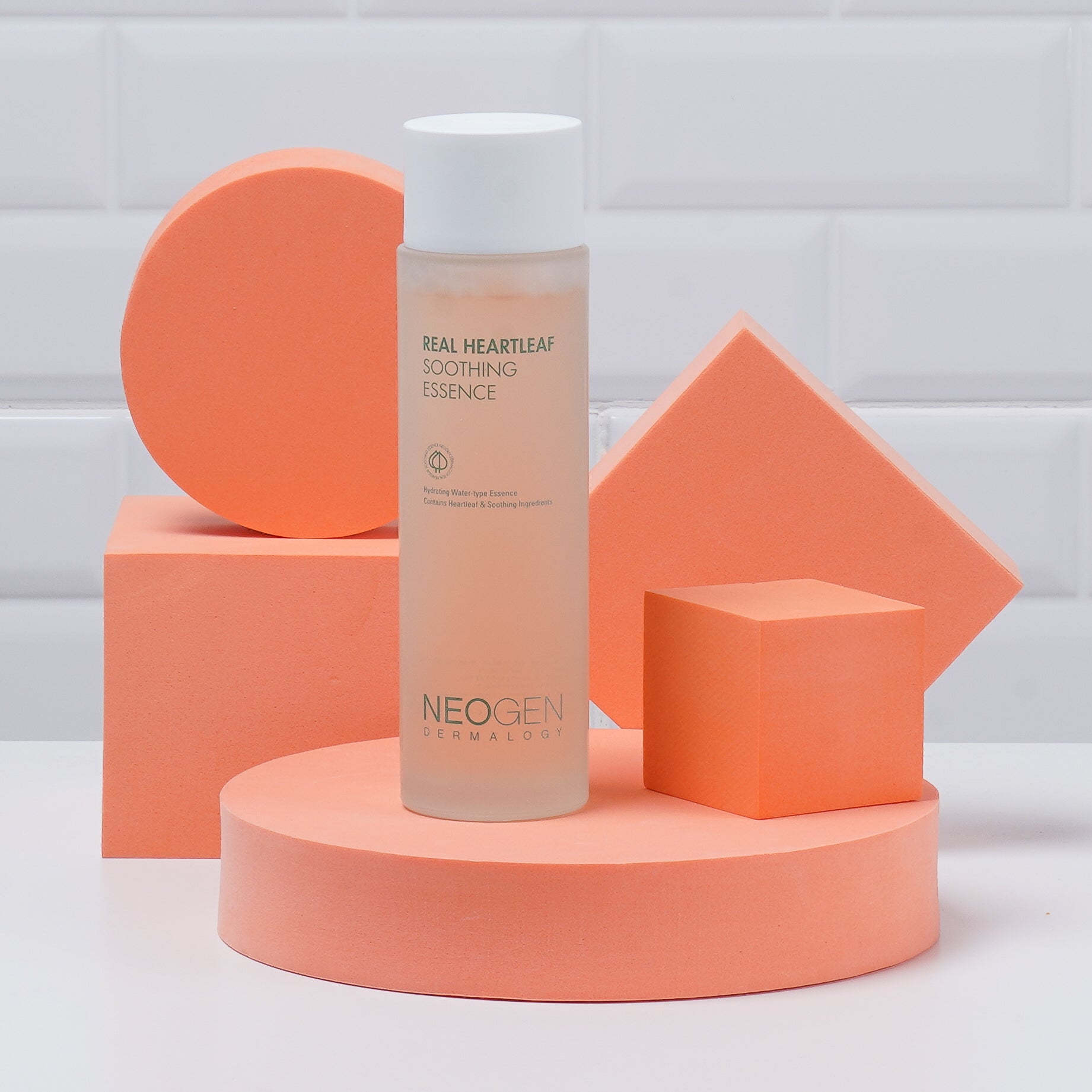 NEOGEN Real Heartleaf Soothing Essence 150ml, flacon sur podium orange en studio, mise en scène beauté.
