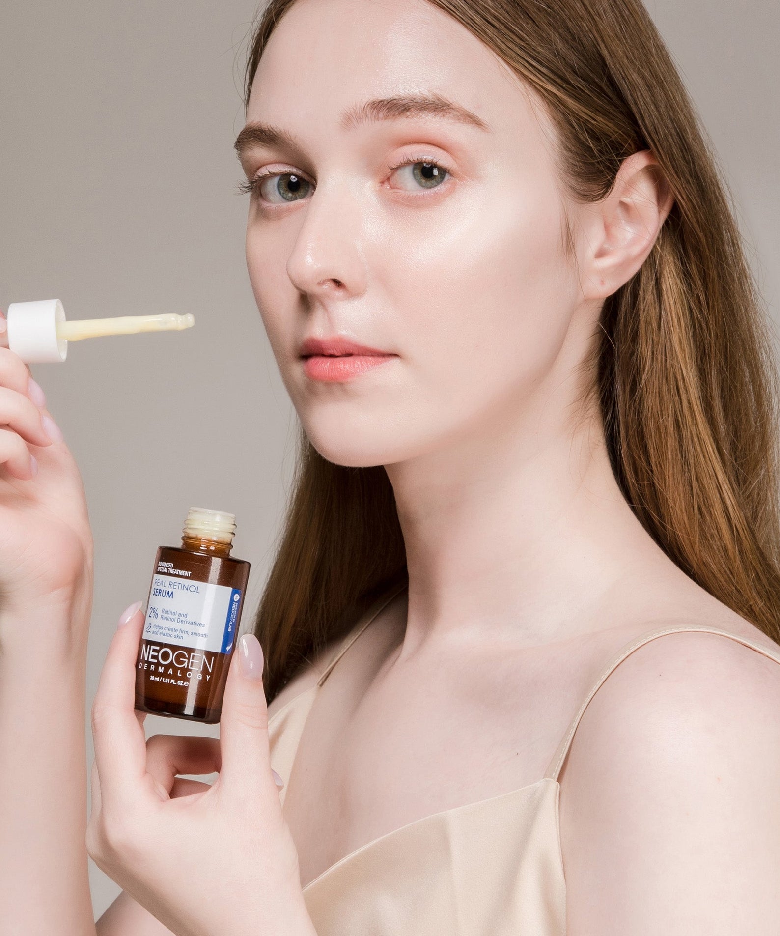 NEOGEN Real Retinol Serum 30ml : femme appliquant le sérum de la marque NEOGEN, flacon et embout goutteur sur fond clair.